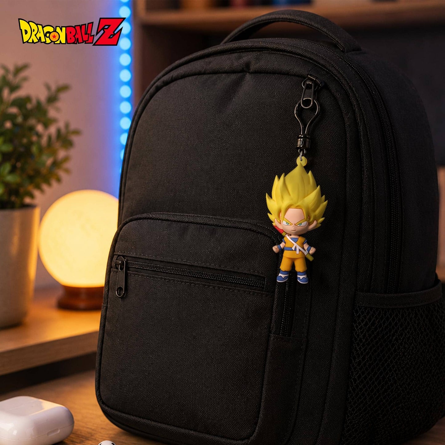 A black backpack with a Dragon Ball Z character charm hanging from the zipper, shown in a warm, dimly lit indoor setting with a glowing lamp and plant in the background.