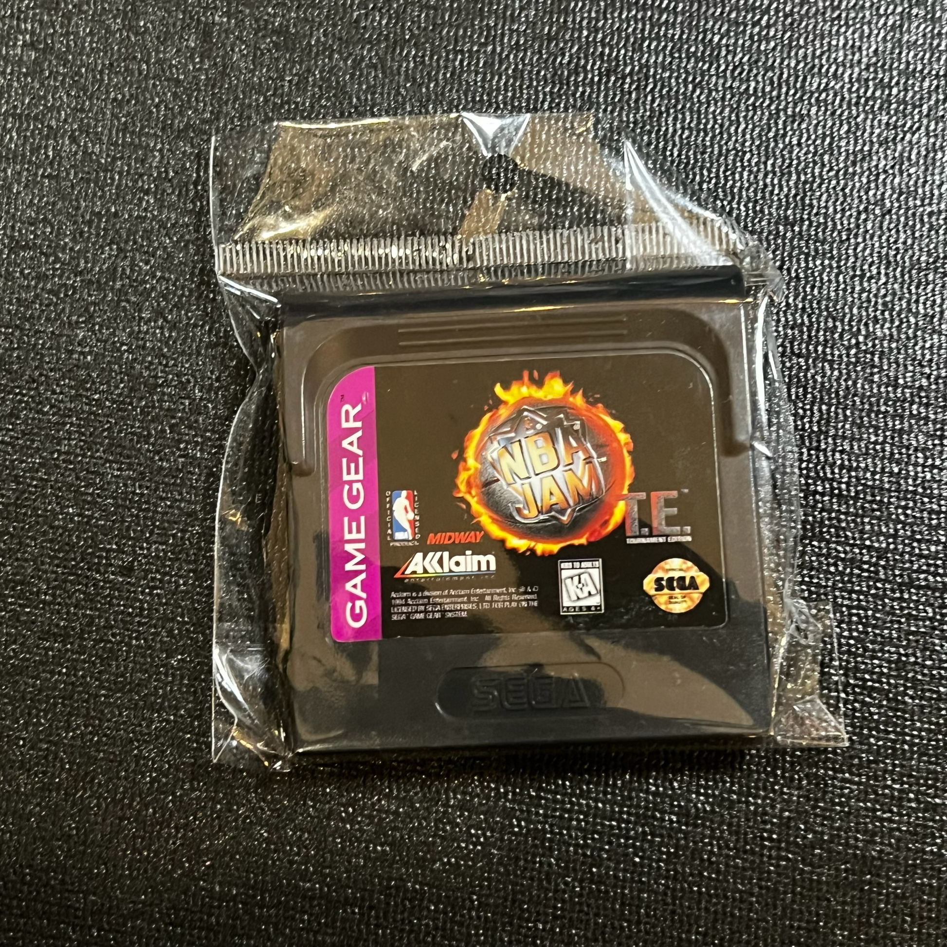 Packaged Game Gear cartridge with NBA Jam logo on a black textured background