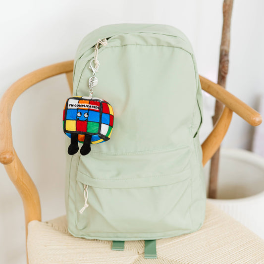 Light green backpack with a colorful keychain on a wooden chair.