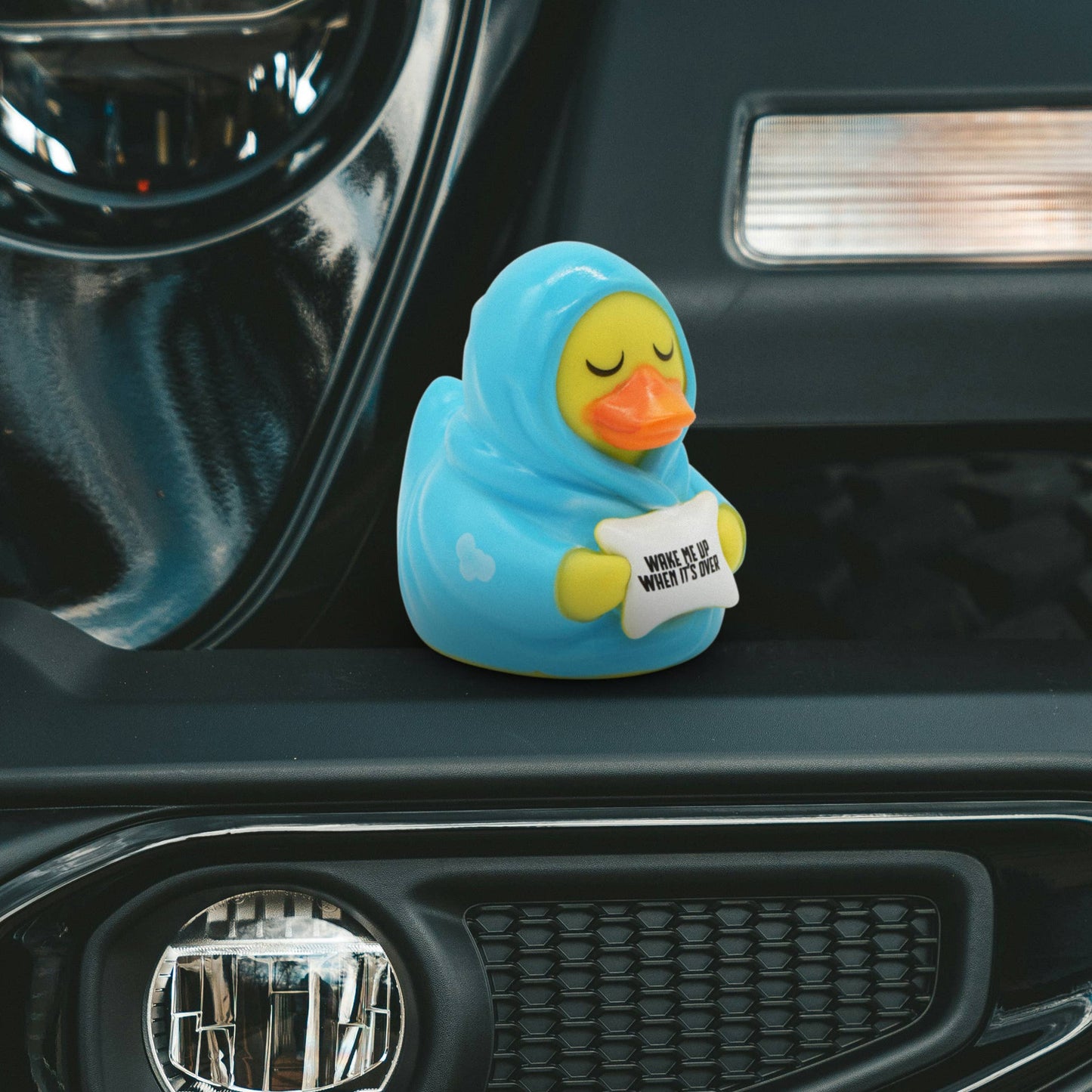 Blue rubber duck with a message tag on a car dashboard